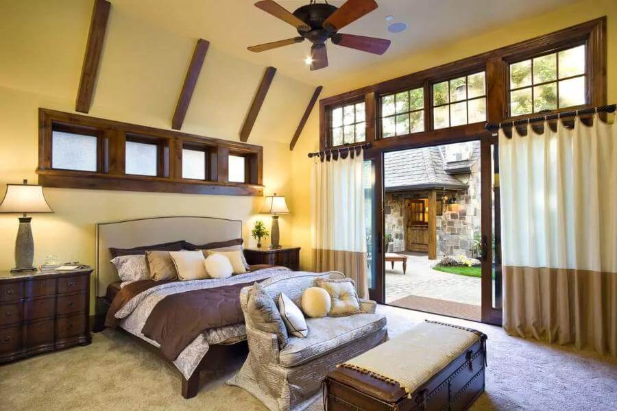 Primary bedroom featuring an upholstered bed, vaulted ceiling, and outdoor access via sliding glass doors.