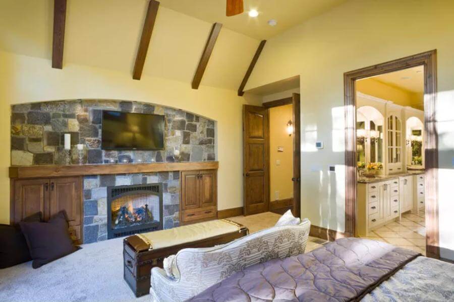 The primary bedroom includes a private bath and stone fireplace with a TV on top.