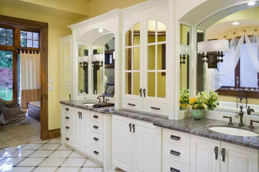 Primary bathroom showcasing a vanity with two sinks and white cabinets.