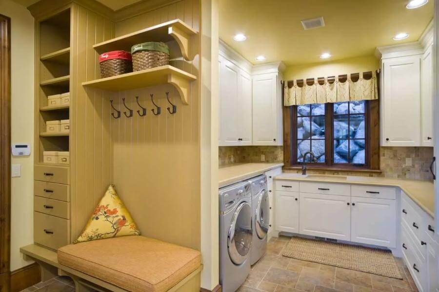 Laundry room featuring white cabinetry, front-load machines, and a cushioned bench.