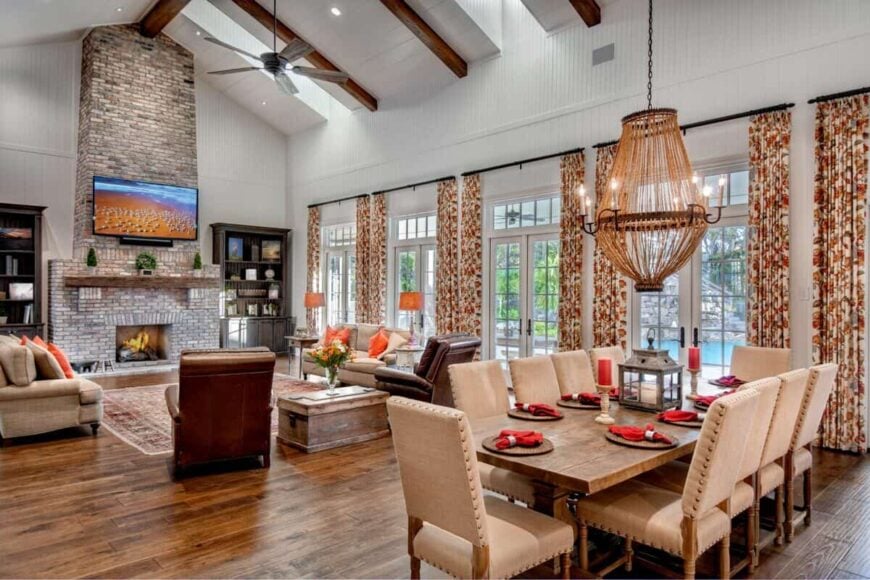 Dining area within the great room featuring beige chairs and a rustic table adorned with an oversized chandelier.