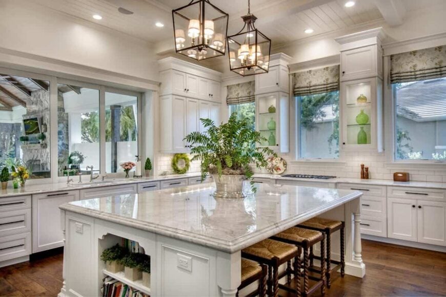 Kitchen equipped with white cabinetry and marble countertops, featuring a breakfast island.