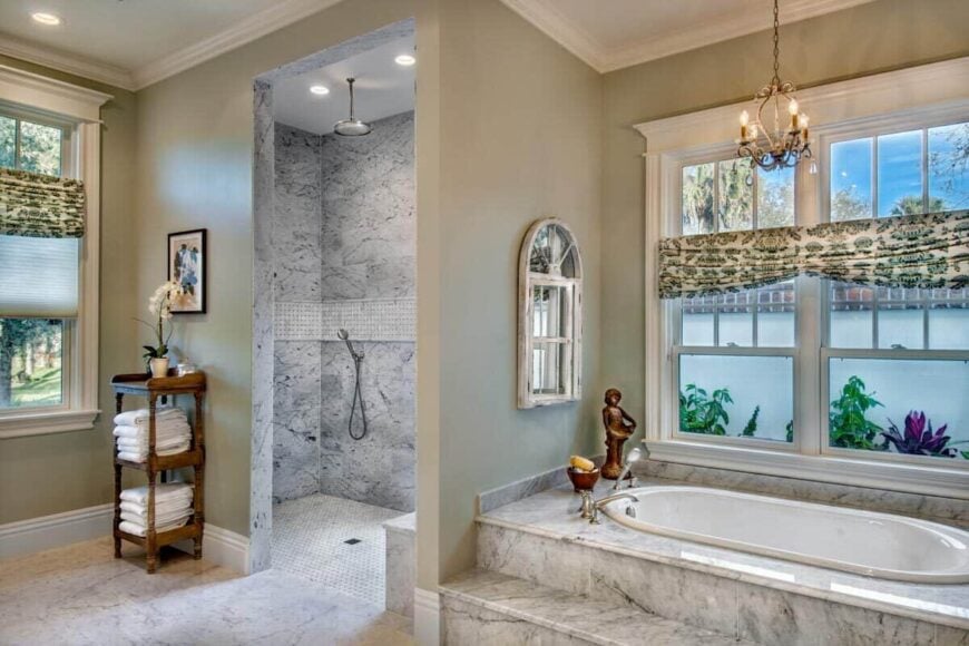 Primary bathroom featuring a walk-in shower and soaking tub illuminated by an ornate pendant light.