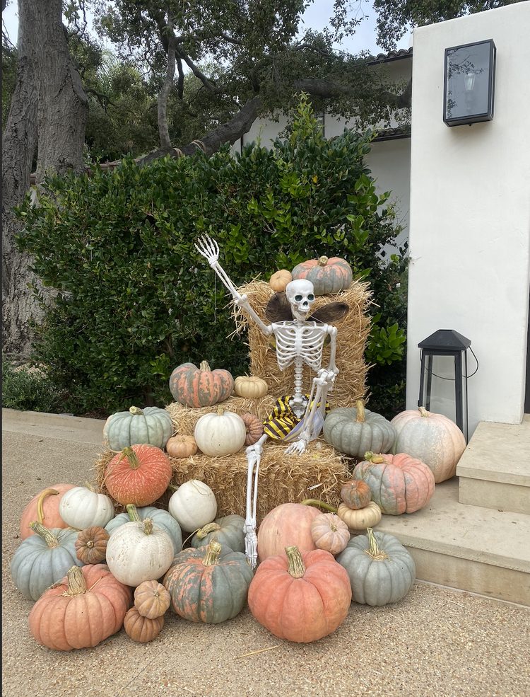 Skeleton sitting on pumpkins and hay bales