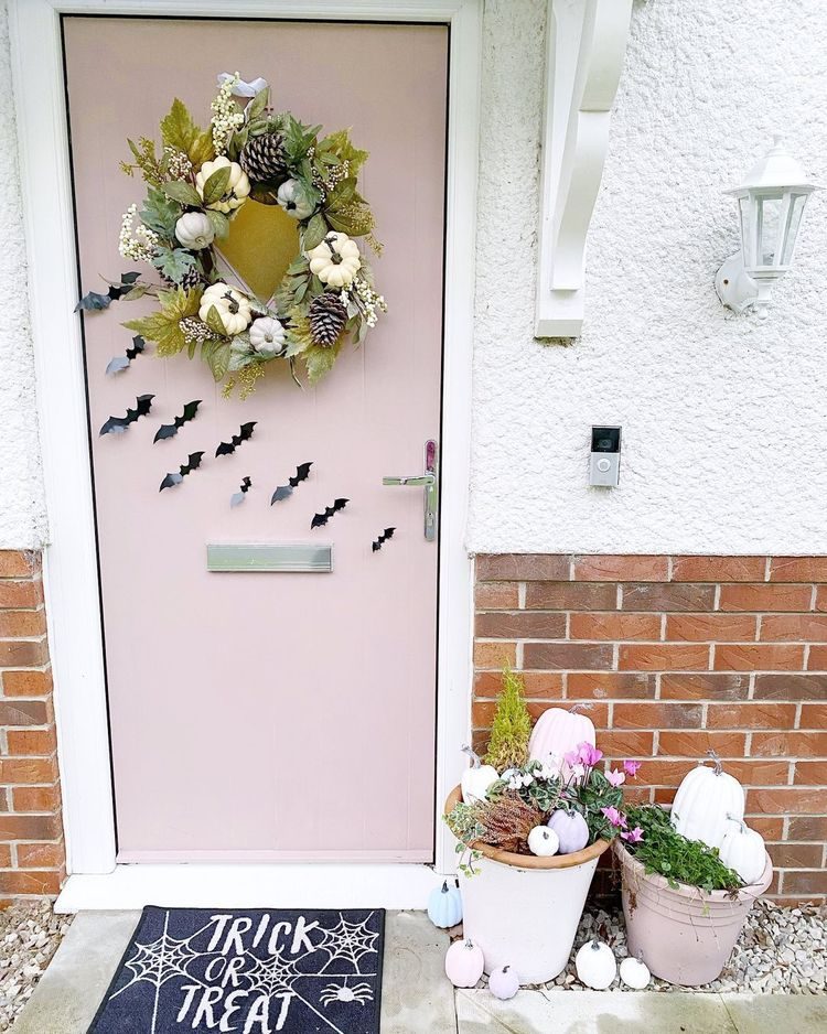 Pink door with pumpkin wreath and bats