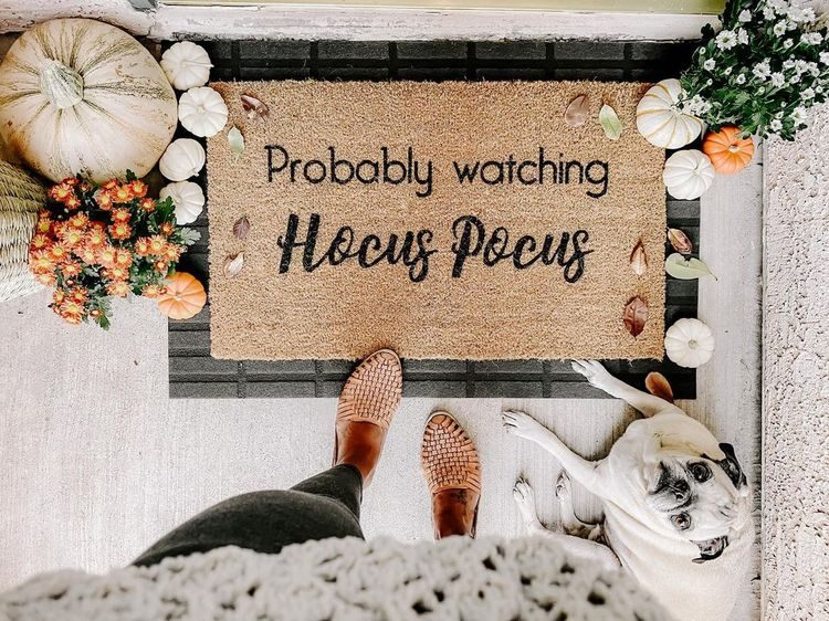 Halloween themed door mat with fall decor around it