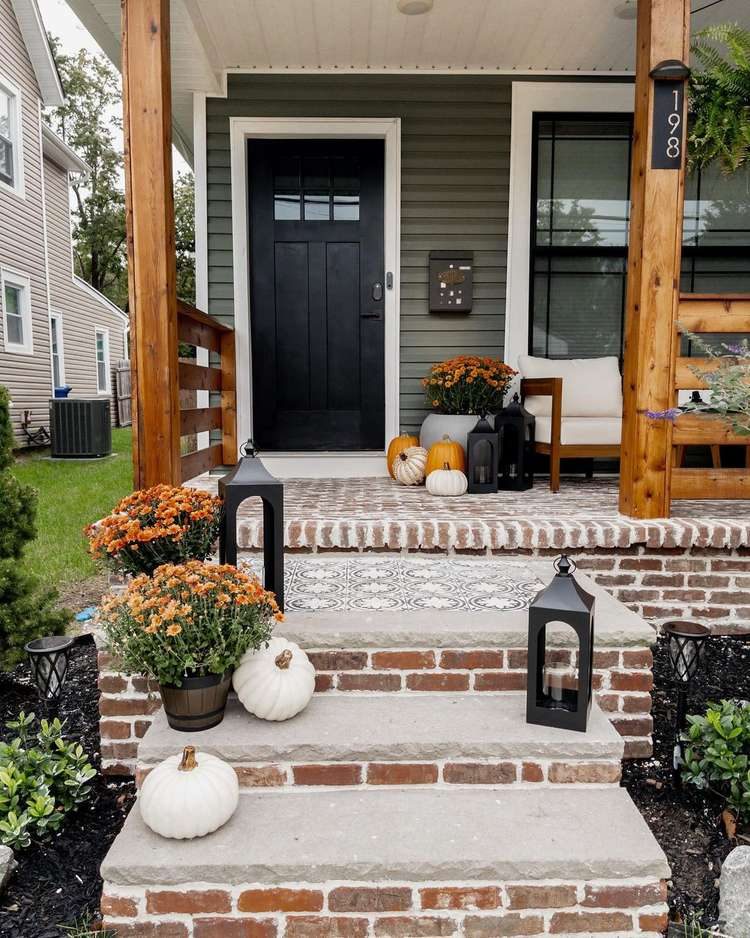 Front porch decorated with black lanterns, mums and pumpkins
