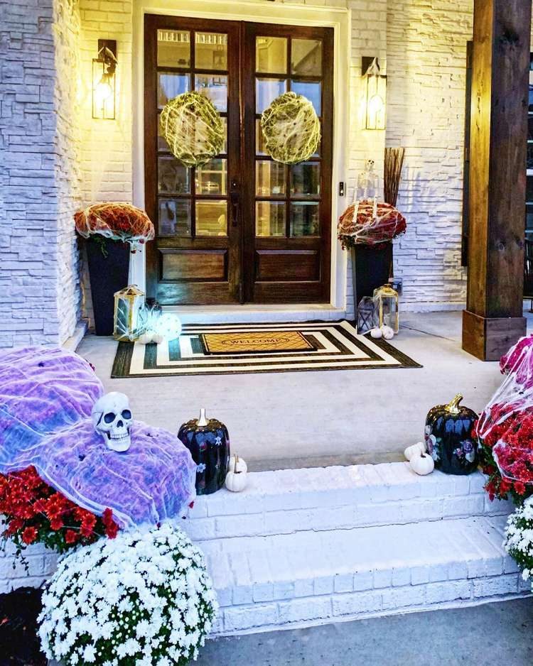Front door decorated with cobwebs on mums, sculls and wreaths