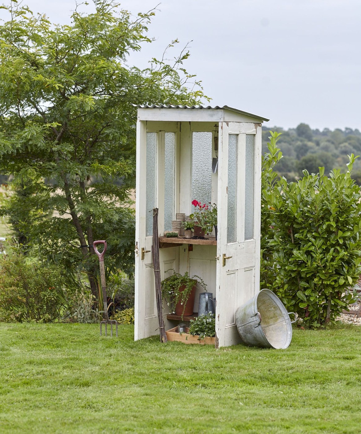 Small white DIY greenhouse made from reclaimed doors