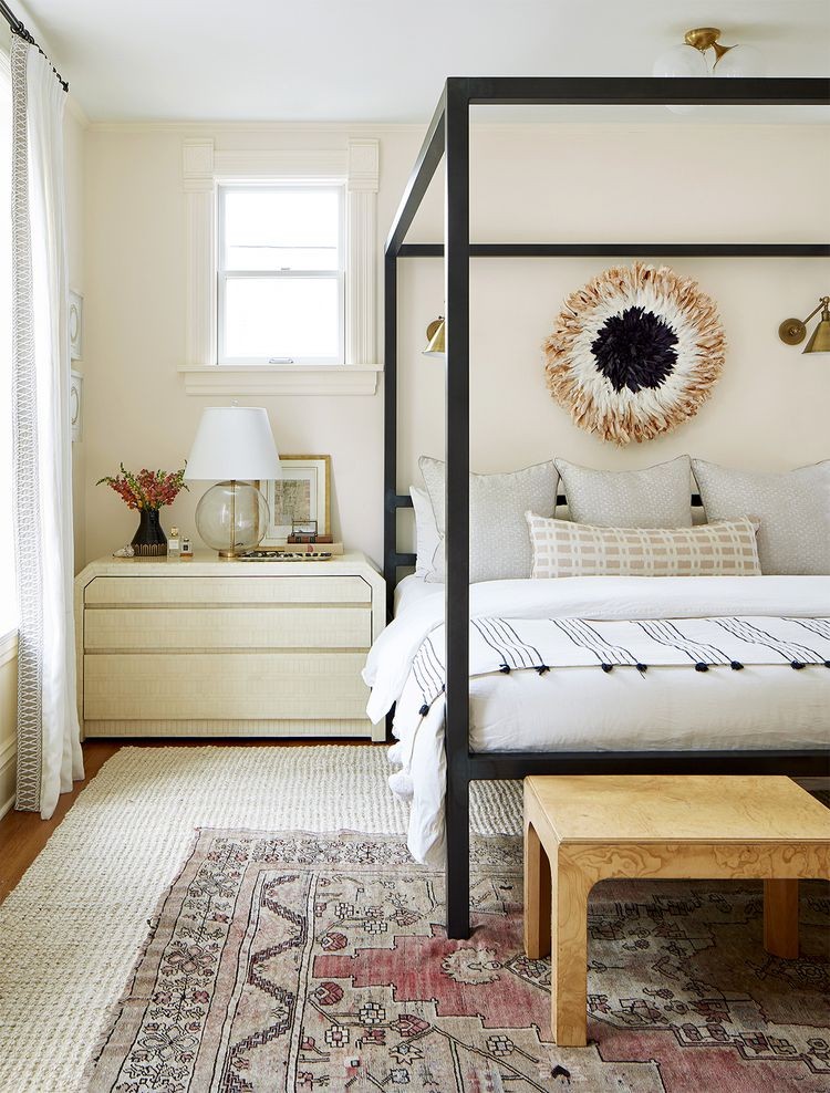 Warm white bedroom with a black four-poster bed