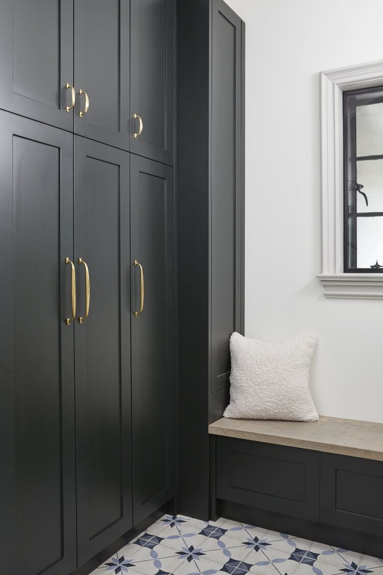 Tall slim dark-painted mudroom cabinets beside a built-in bench