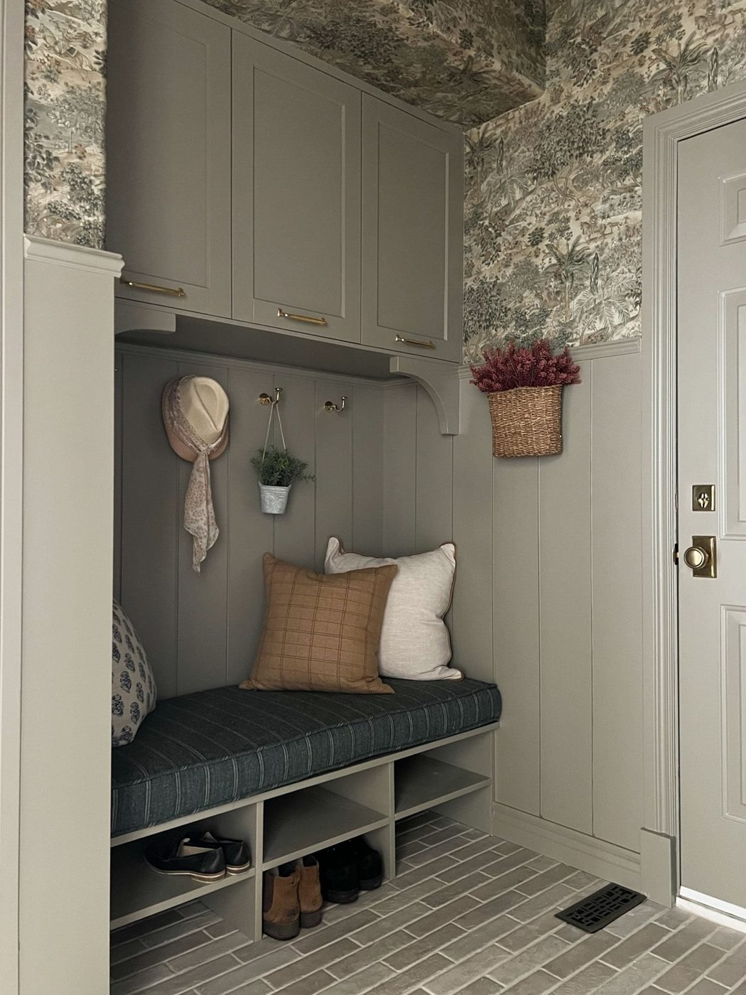 Small mudroom alcove with a built-in bench, cubbies and hooks under upper cabinets