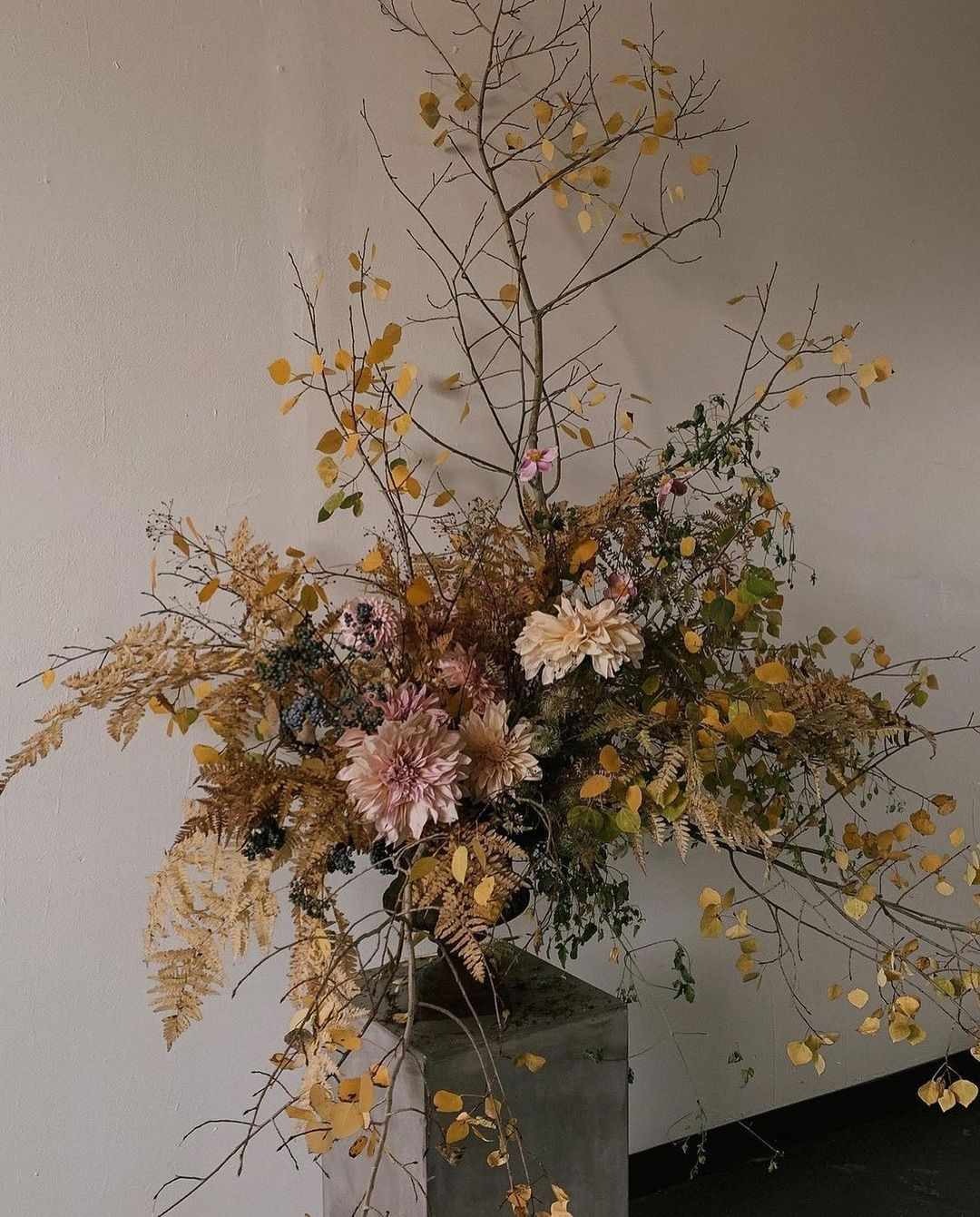 Tall vase of preserved autumn branches, dried flowers and wispy stems in muted fall tones